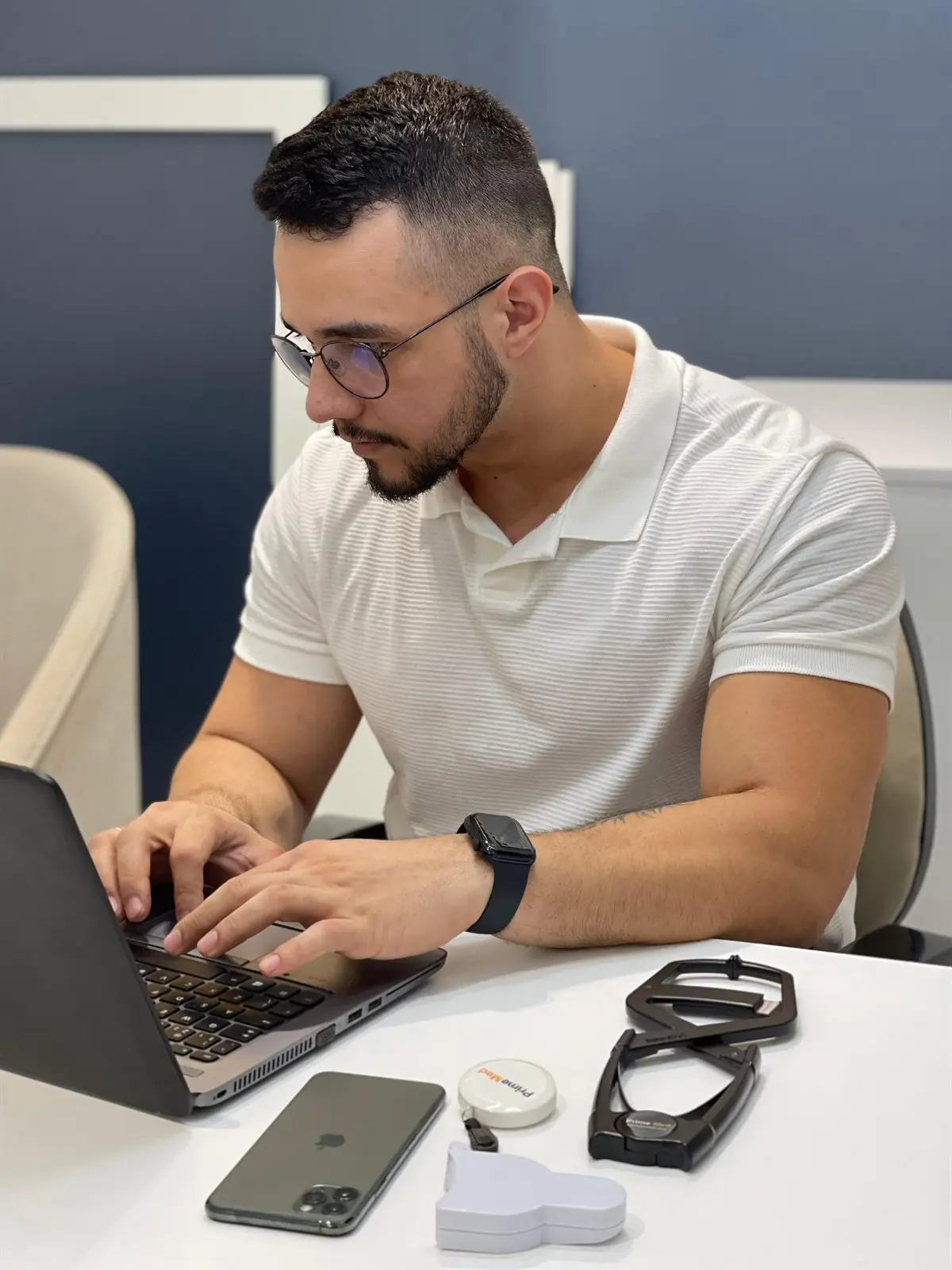 João Marcelo ao computador, com o material de avaliação física na mesa