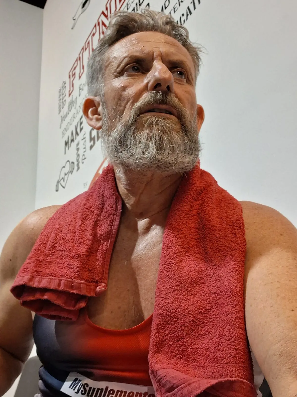 Sócio de barba grisalha, com a toalha ao pescoço depois do treino