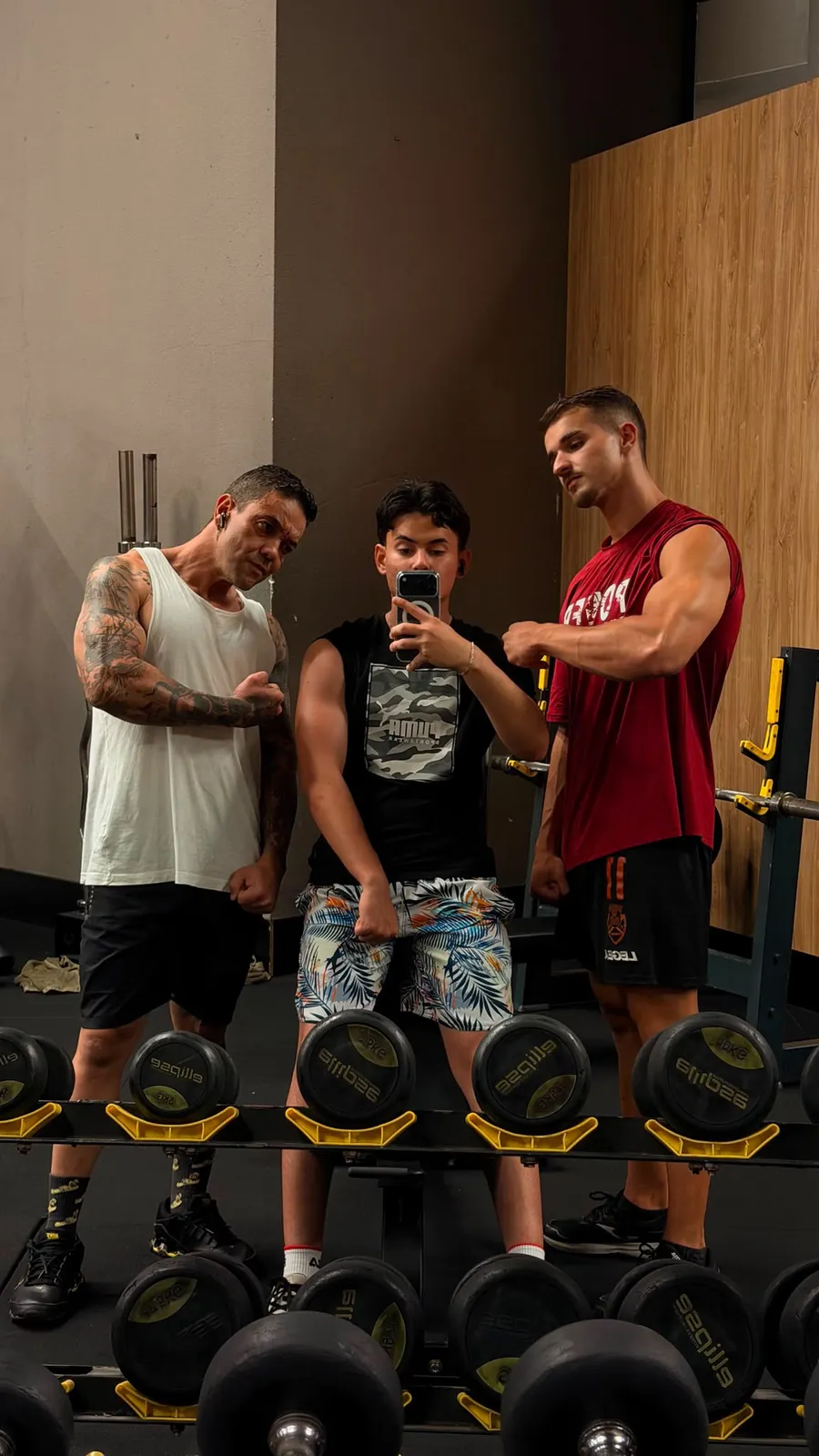 Três sócios a fazer pose ao espelho do ginásio